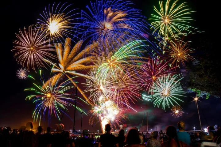 nsw-events Spectacular fireworks lighting up the night sky over a coastal crowd enjoying NSW events during summer celebrations.