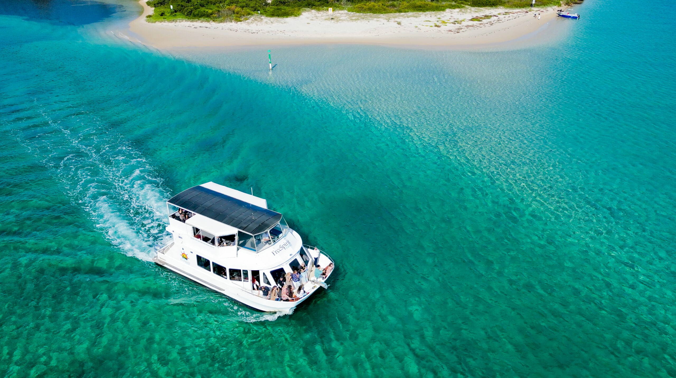Screenshot Aerial view of FreeSpirit Cruises boat on calm Wallis Lake with turquoise water and sandy islands, Forster NSW